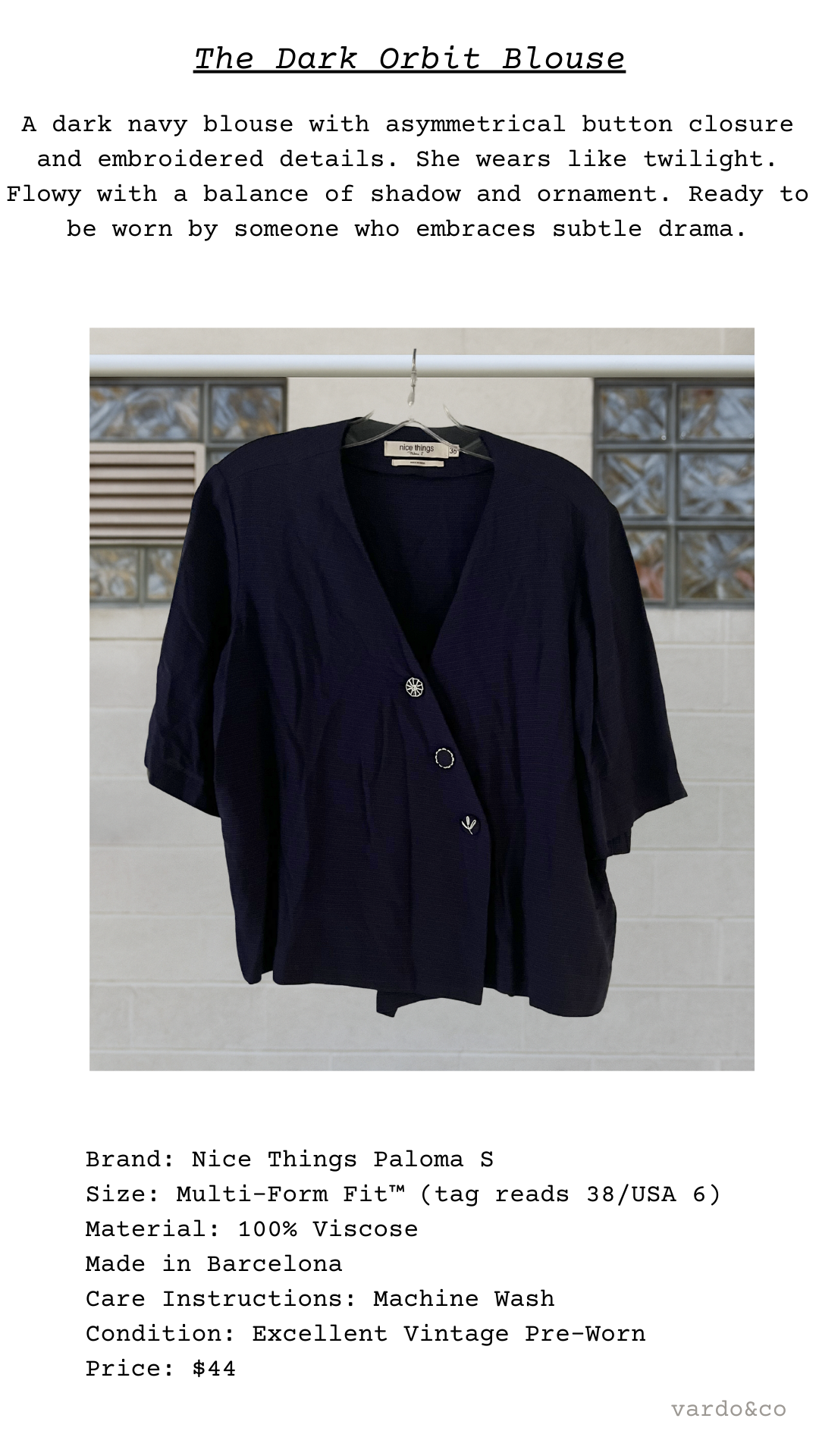 Dark navy blouse with button closure on a hanger against a light background