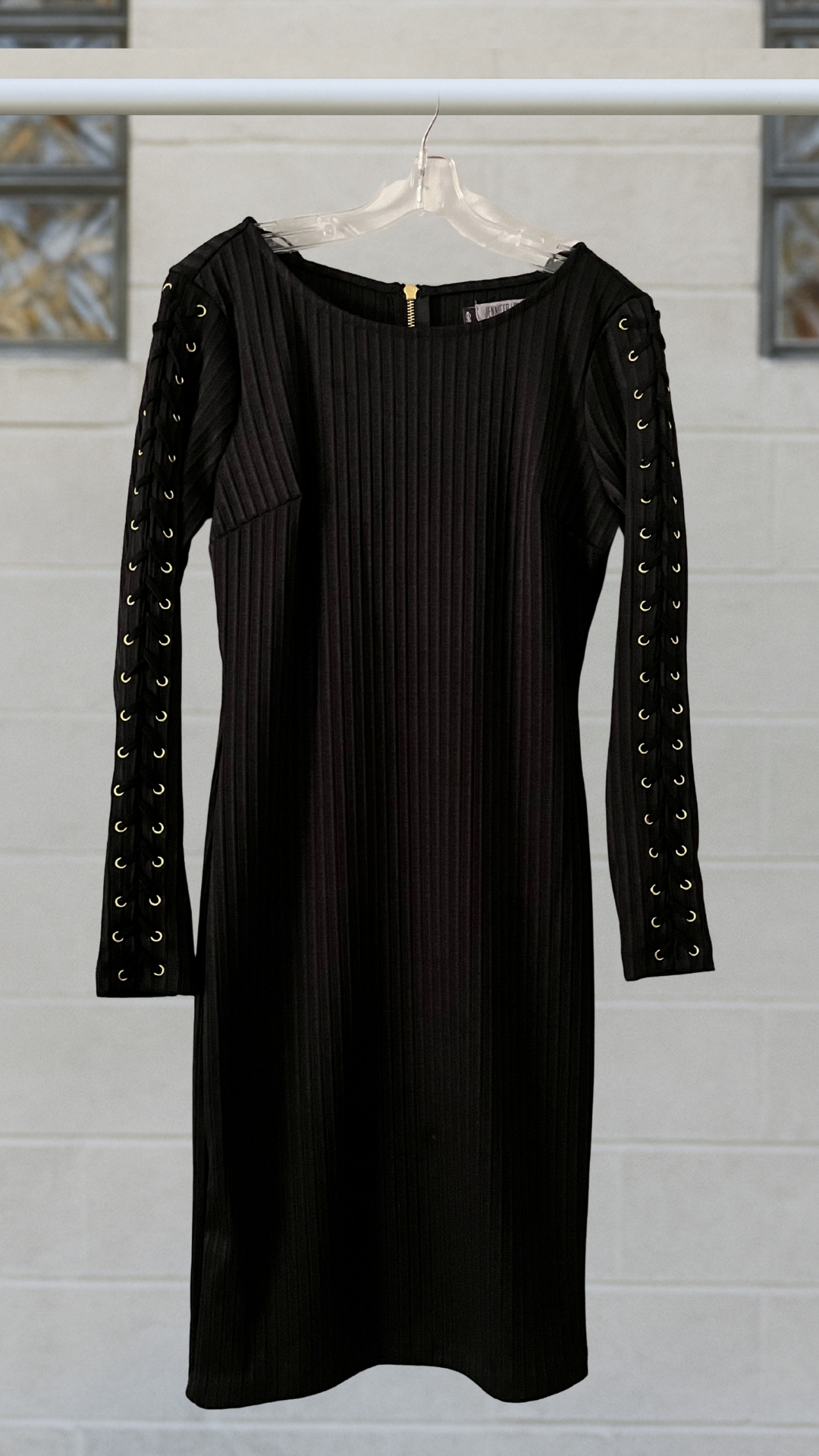 A black ribbed bodycon dress with gold grommet long sleeves and a bold zipper back