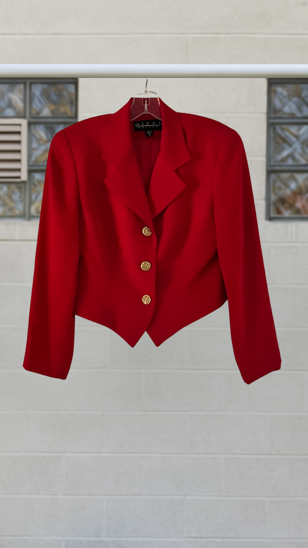 a couture cropped blazer on a hanger against a white background