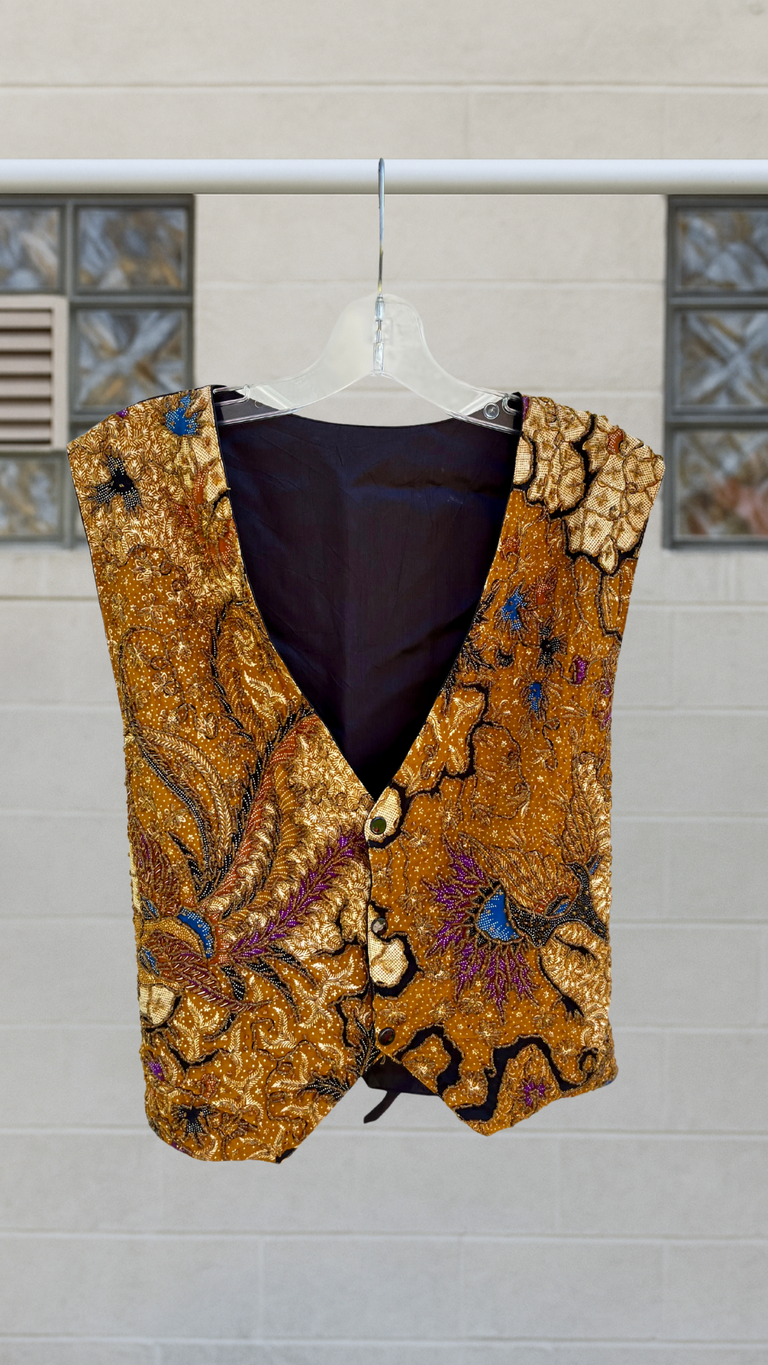 a colorful beaded vest on a hanger against a white background