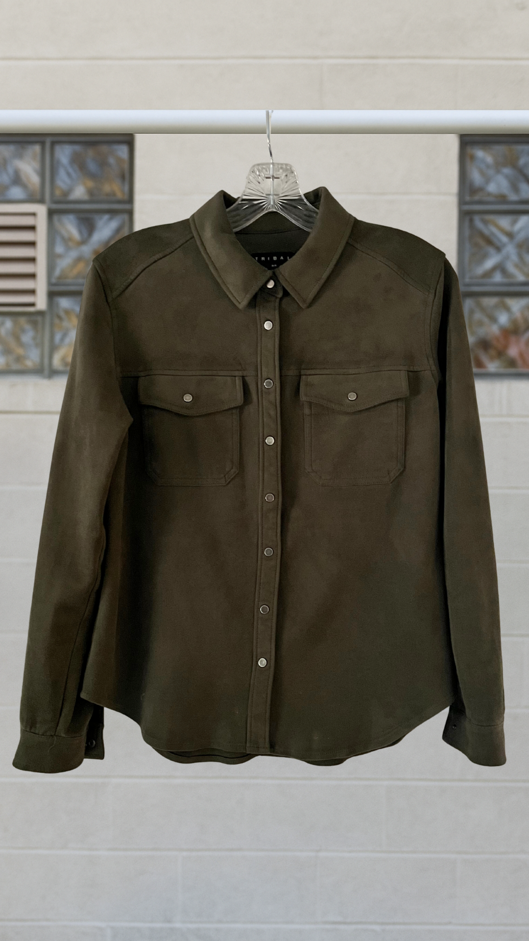 a green velvet-like long sleeve shirt on a hanger against a white background