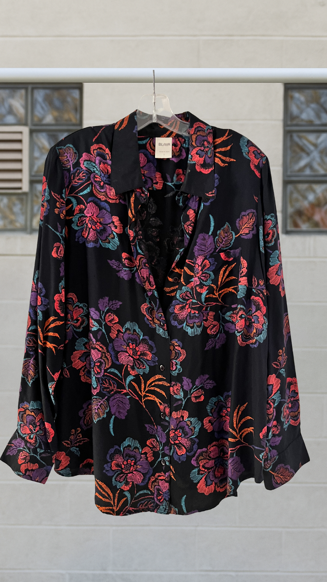 a black and pink button down shirt on a hanger against a white background
