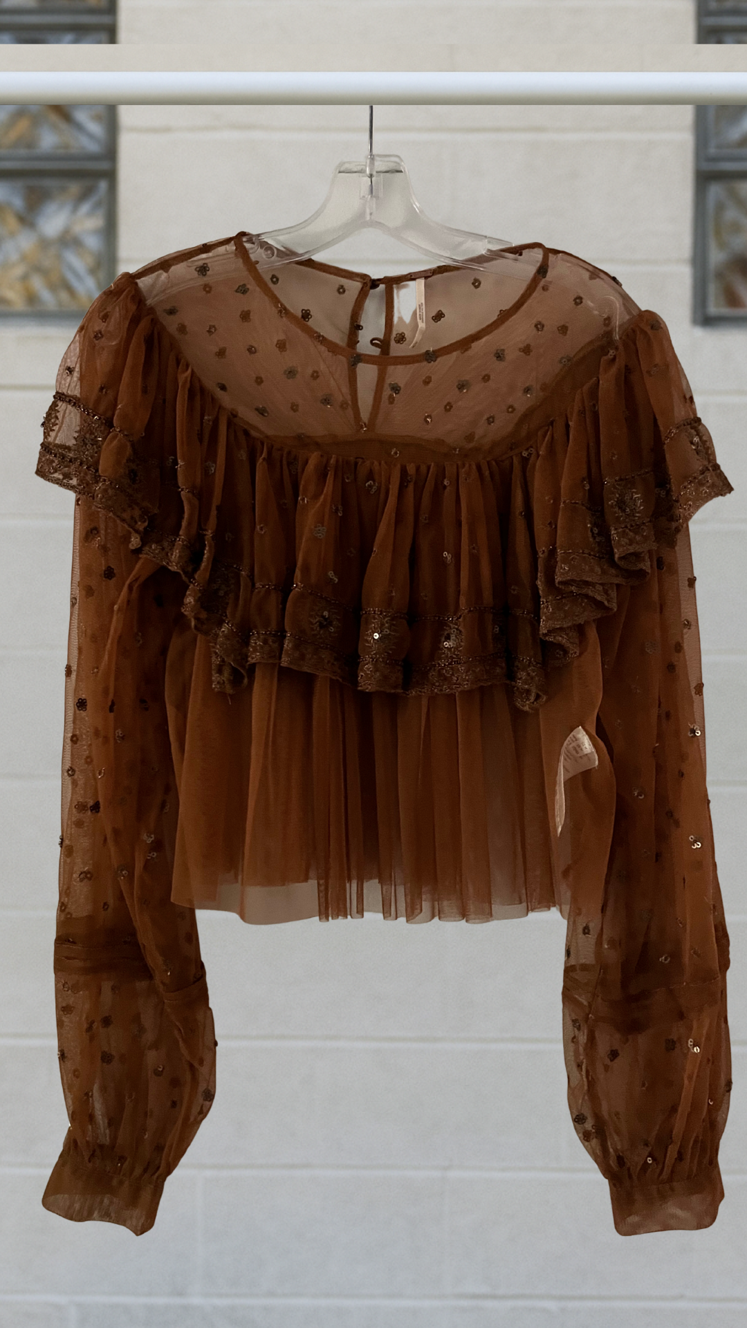a boho top on a hanger against a white background