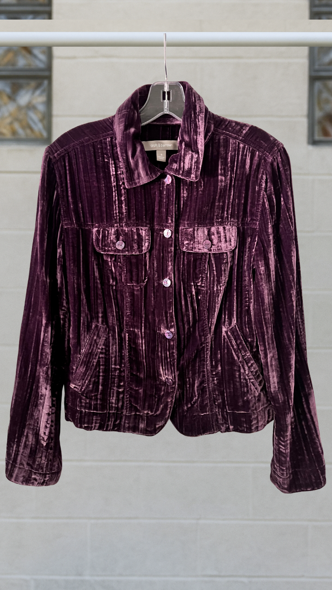 a purple velvet shirt on a hanger against a white background