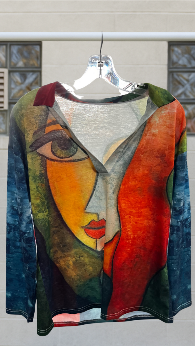 a long sleeve shirt with a lady's face on a hanger against a white wall