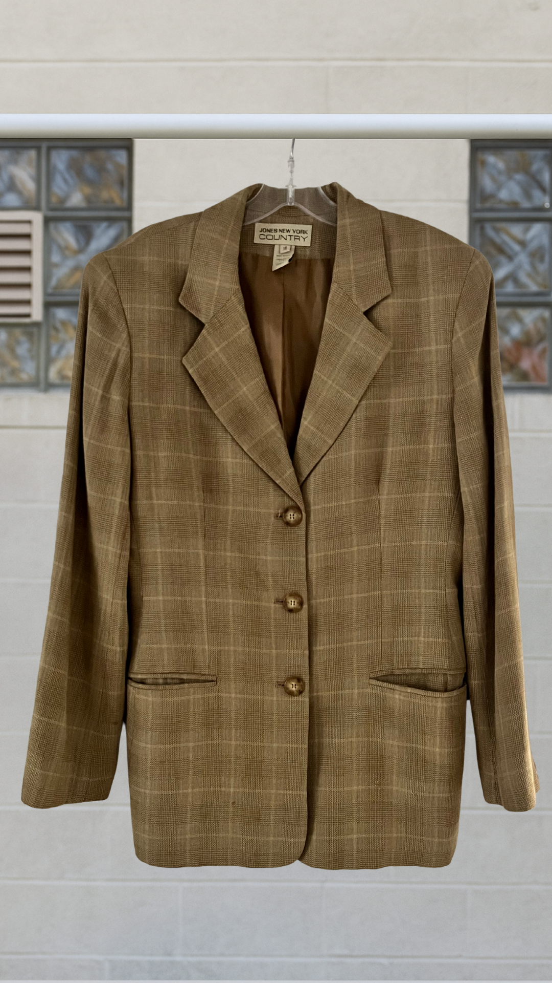 a brown blazer on a hanger against a white background