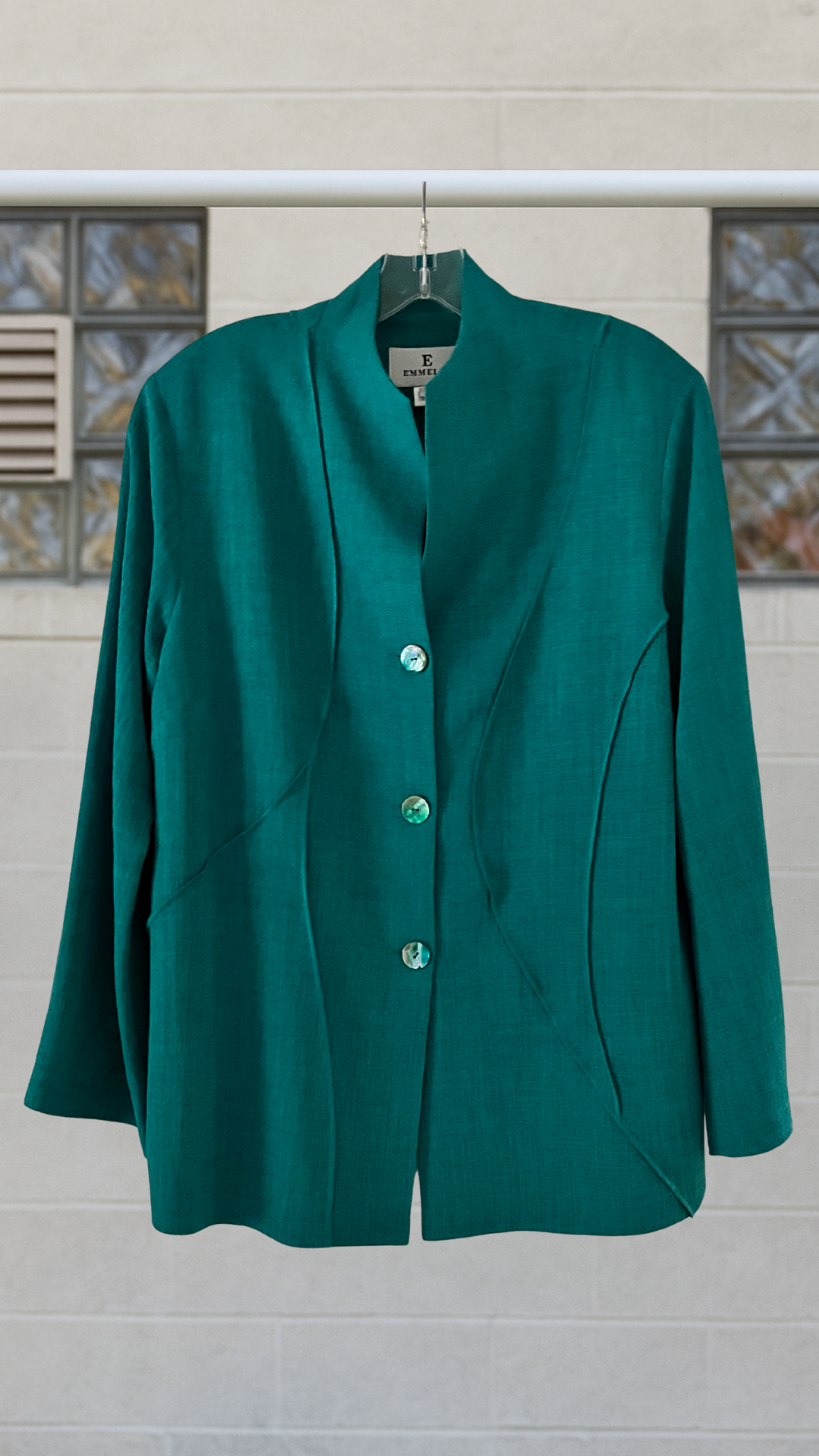 a teal jacket on a hanger against a white background