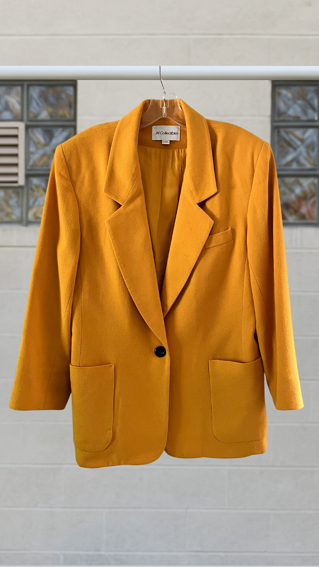 a marigold blazer on hanger against a white background