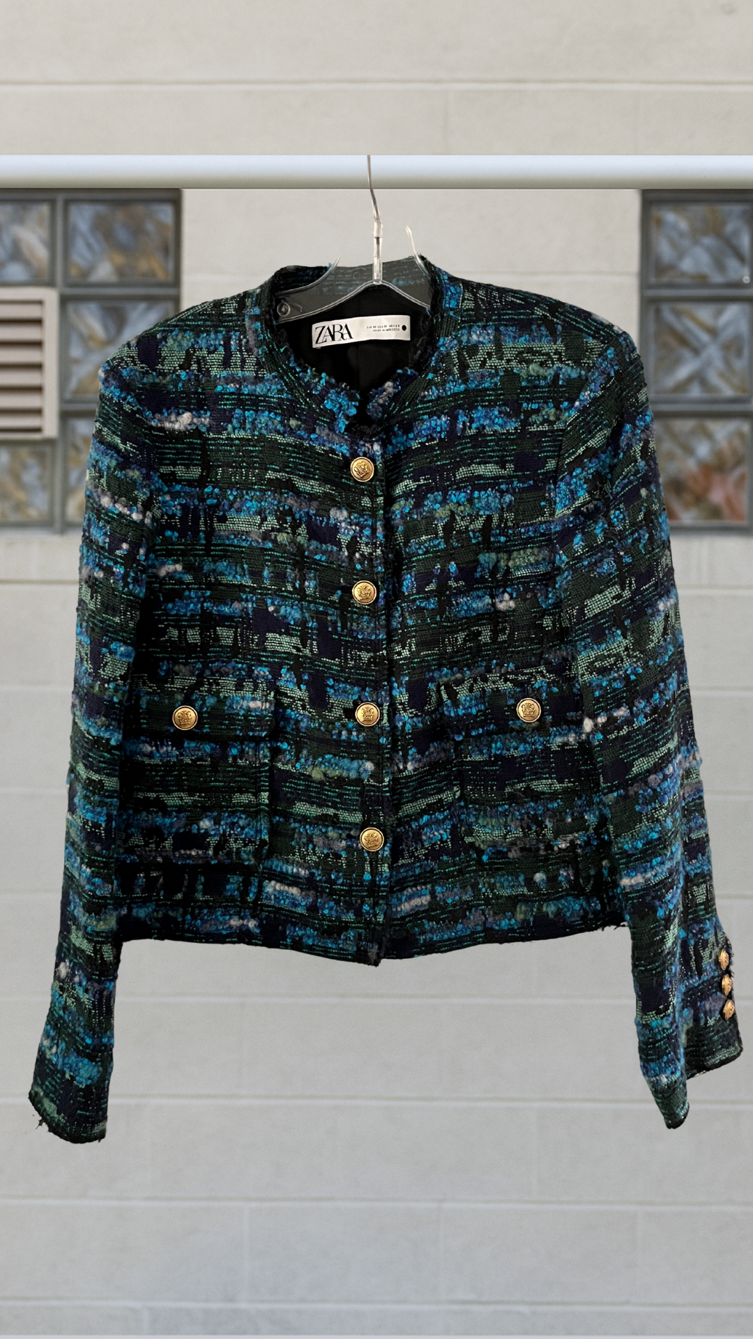 a Chanel style moto jacket on a hanger against a white background