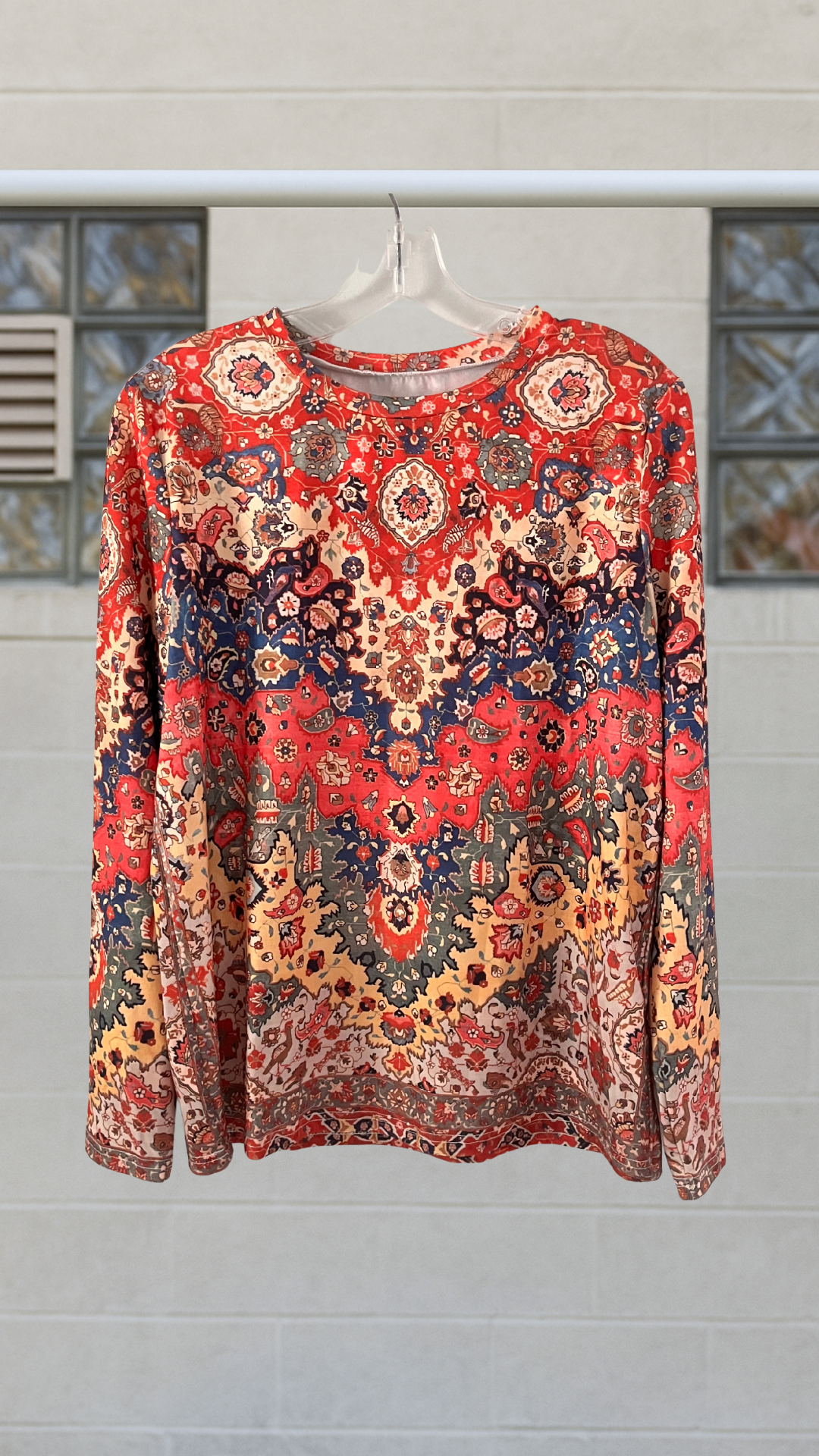a tapestry colored long sleeve shirt on a hanger against a white background