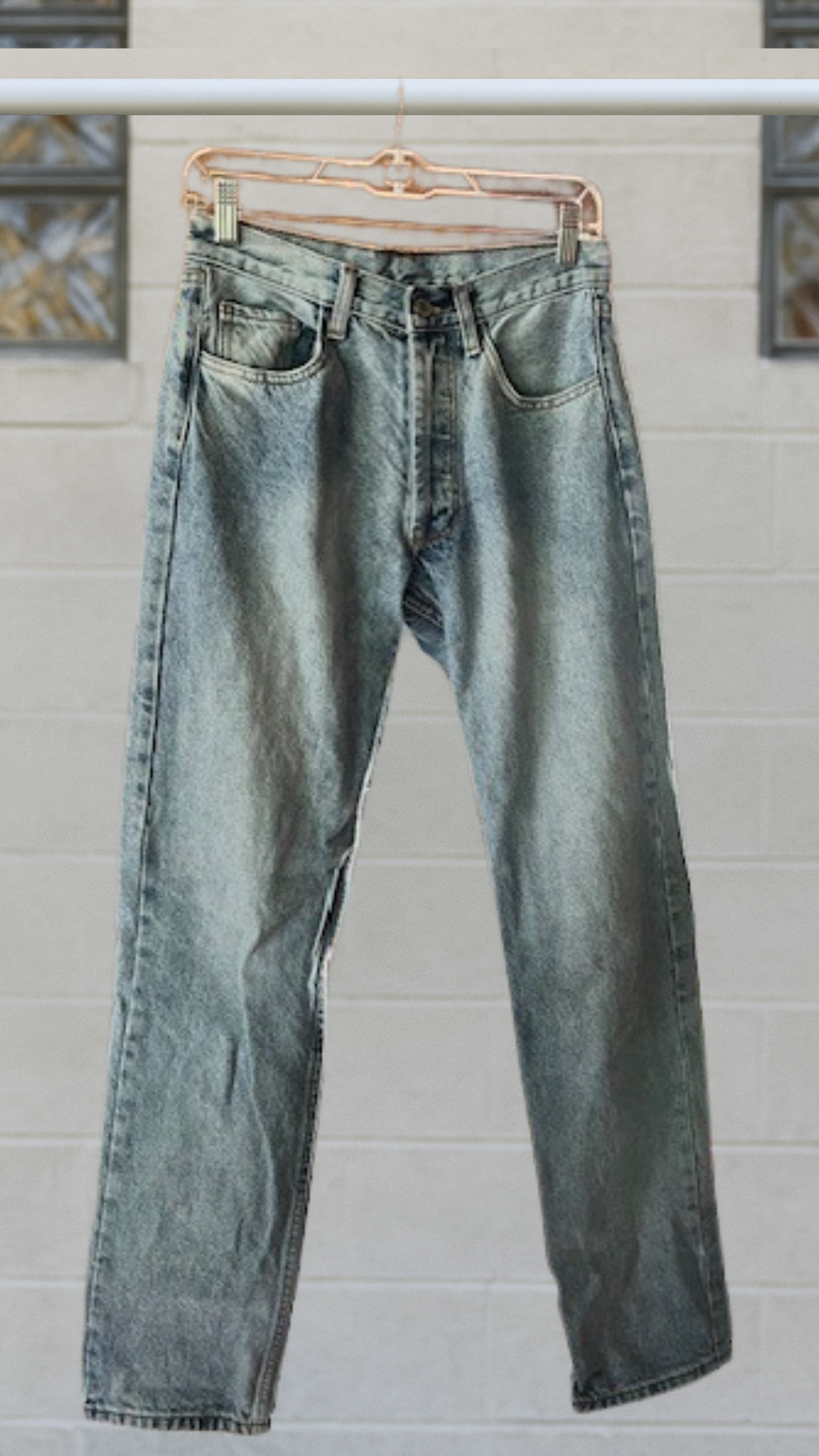 denim jeans on a hanger against a white background