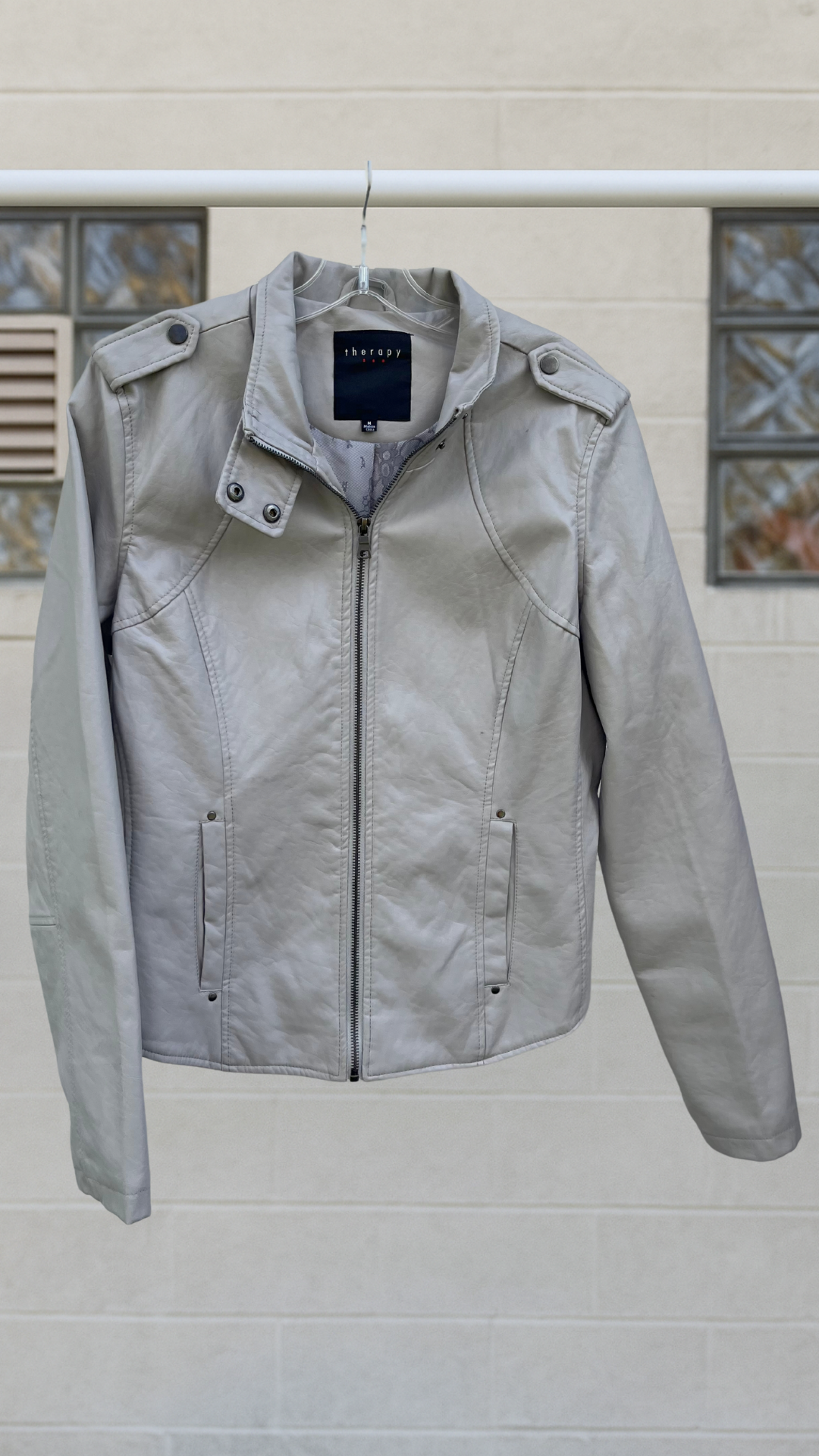 a leather-like Moto jacket on a hanger against a white background
