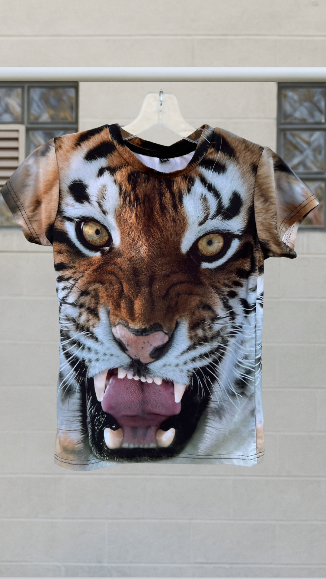 a short sleeve top with a tiger face on it on a hanger against a white background