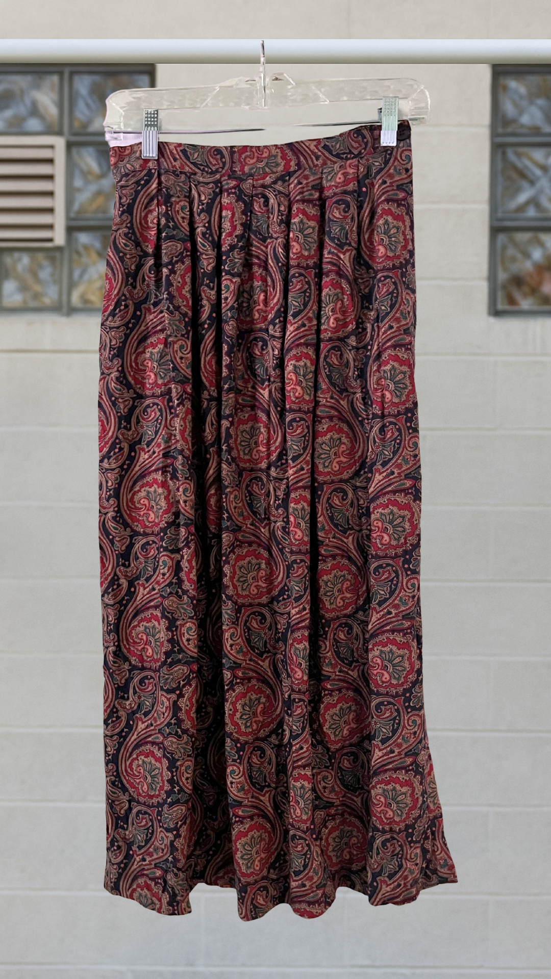 a purple paisley skirt on a hanger against a white background