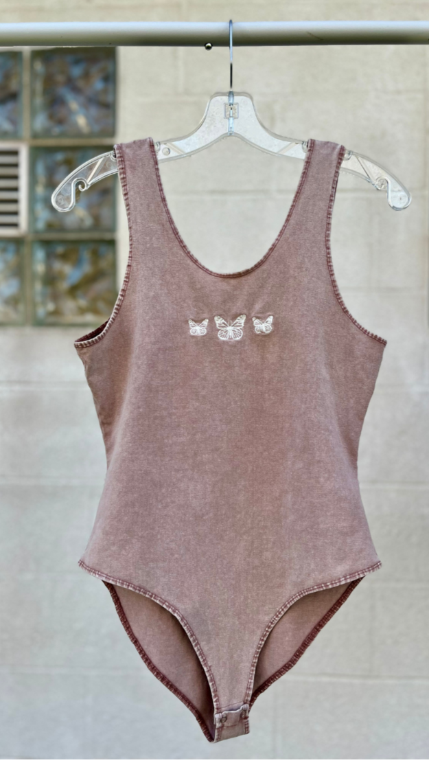a purple white washed bodysuit on a hanger against a white background