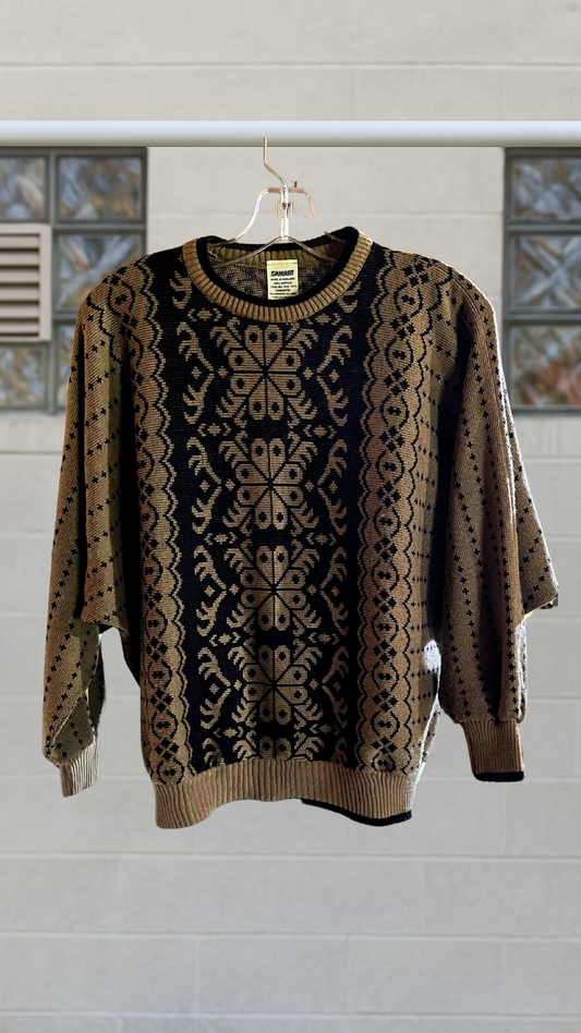 Vintage Damart sweater with central mirrored motif and ribbed hem, hanging on a clear hanger against a tiled neutral wall.