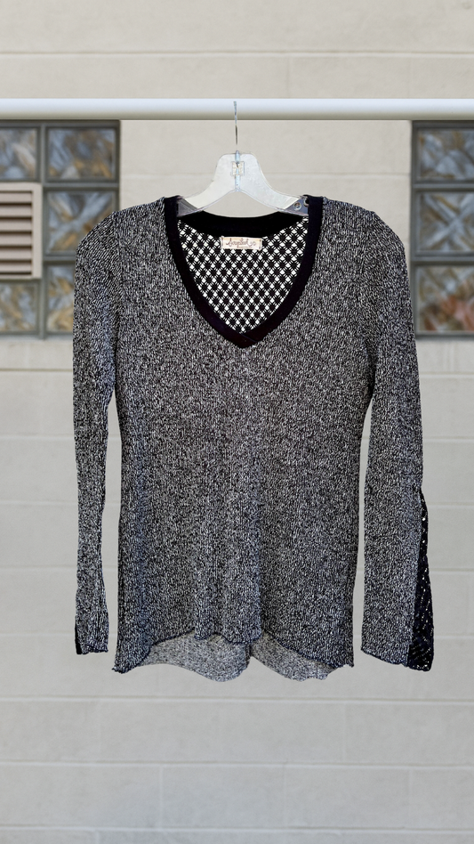 Black and white textured knit shirt with diamond lace back and bell sleeves, hanging on hanger outdoors