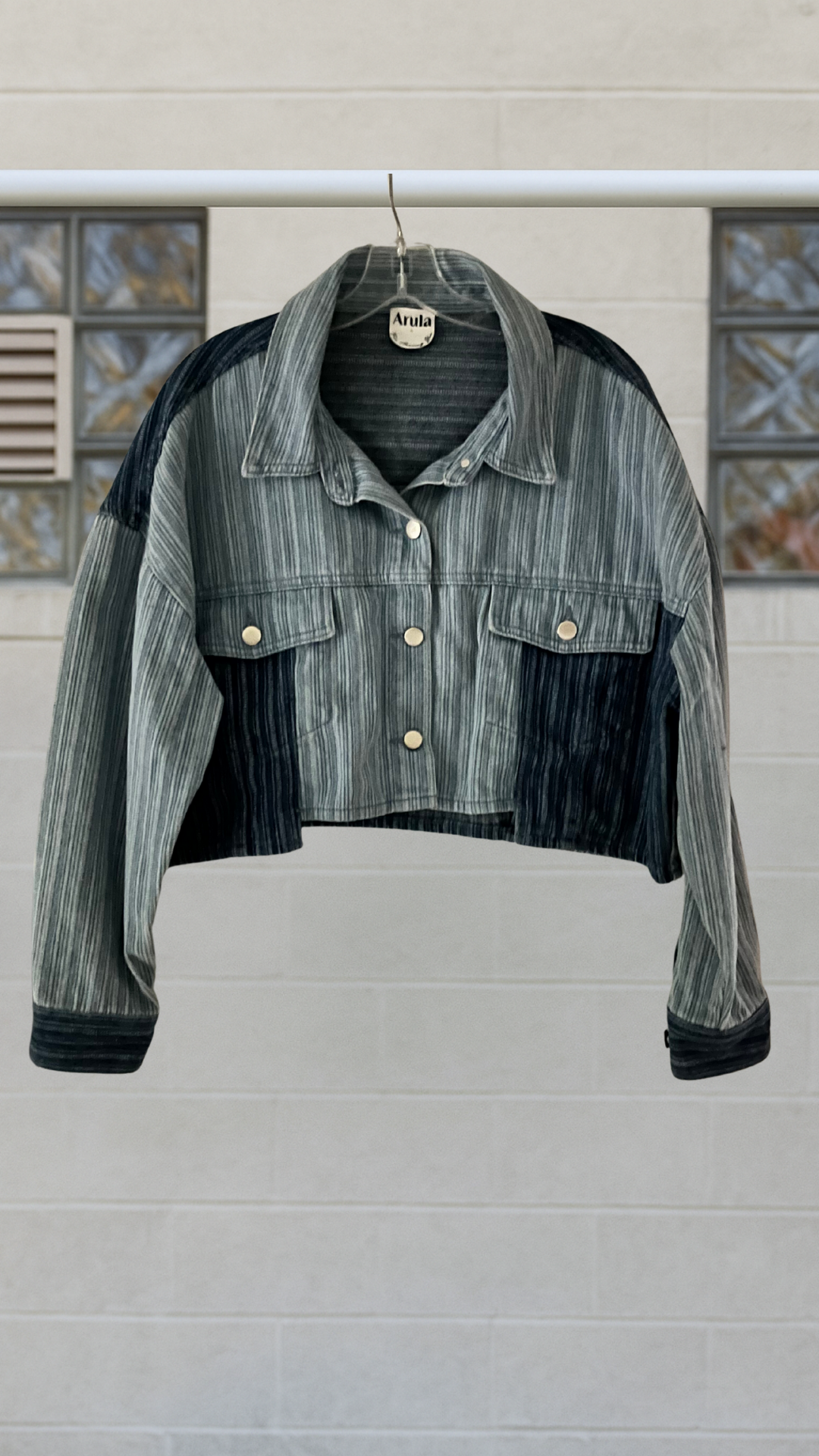 Denim jacket with contrast accents on a hanger against a neutral background