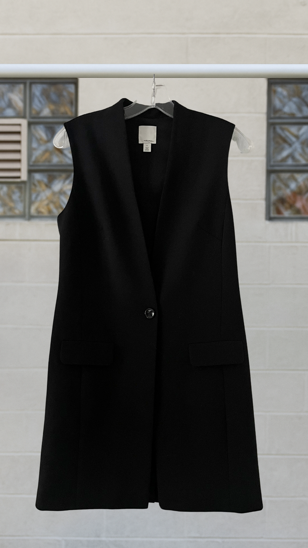 Black vest on a hanger against a tiled wall background