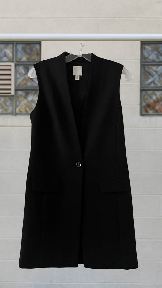 Black vest on a hanger against a tiled wall background