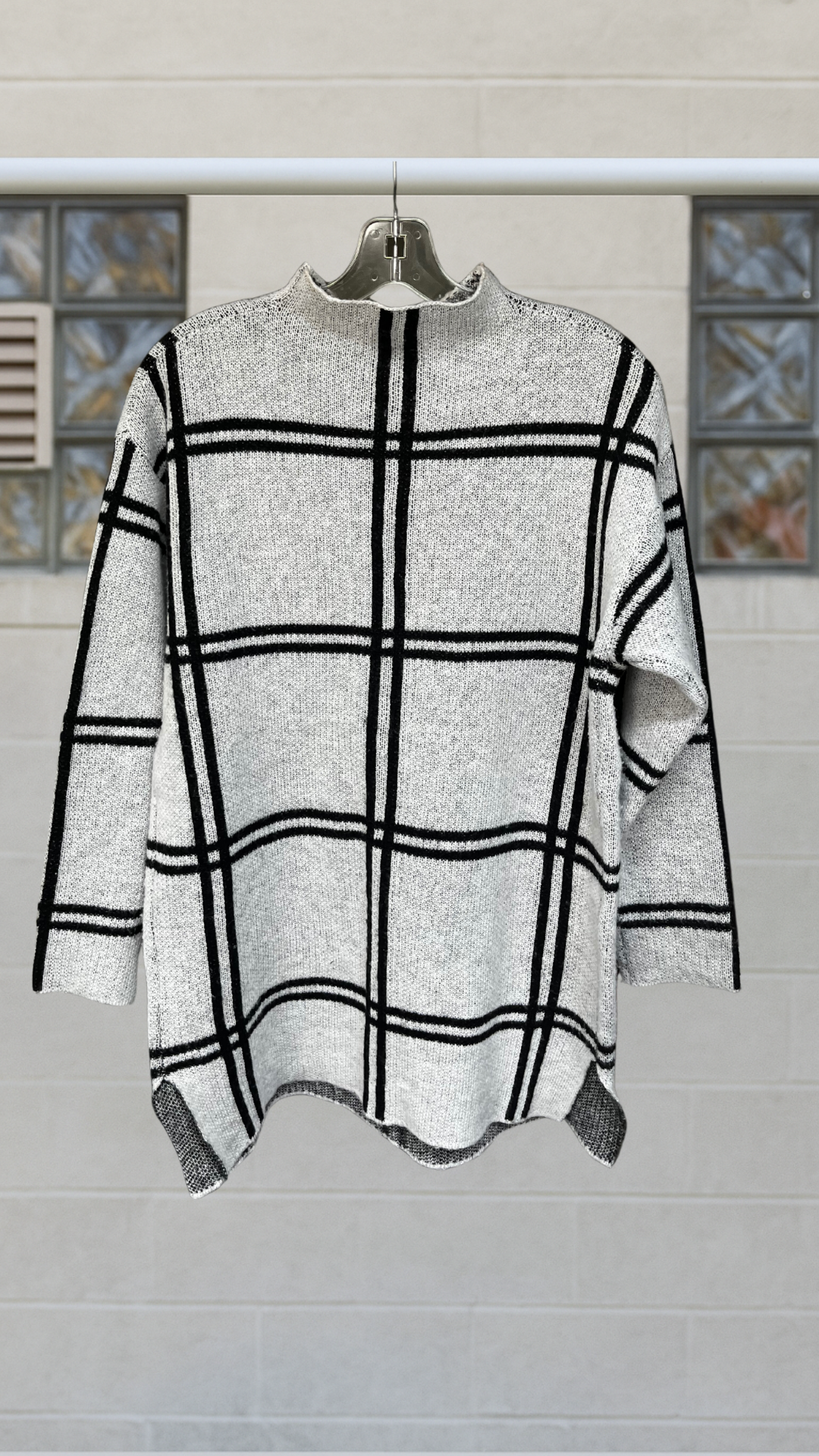 Gray sweater with black windowpane grid, mock neck, and side slits.