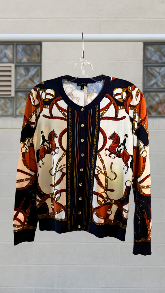 Long sleeve printed cardigan with ornate equestrian motif in red, navy, and cream, featuring horses and gold chain patterns, hanging on a hanger.