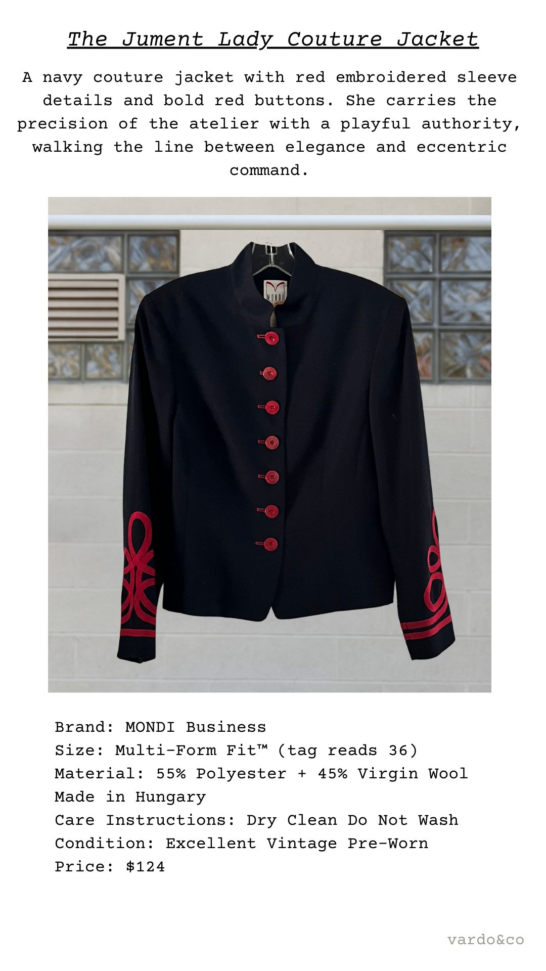 Navy couture jacket with red buttons and embroidered sleeves on a hanger against a neutral background.