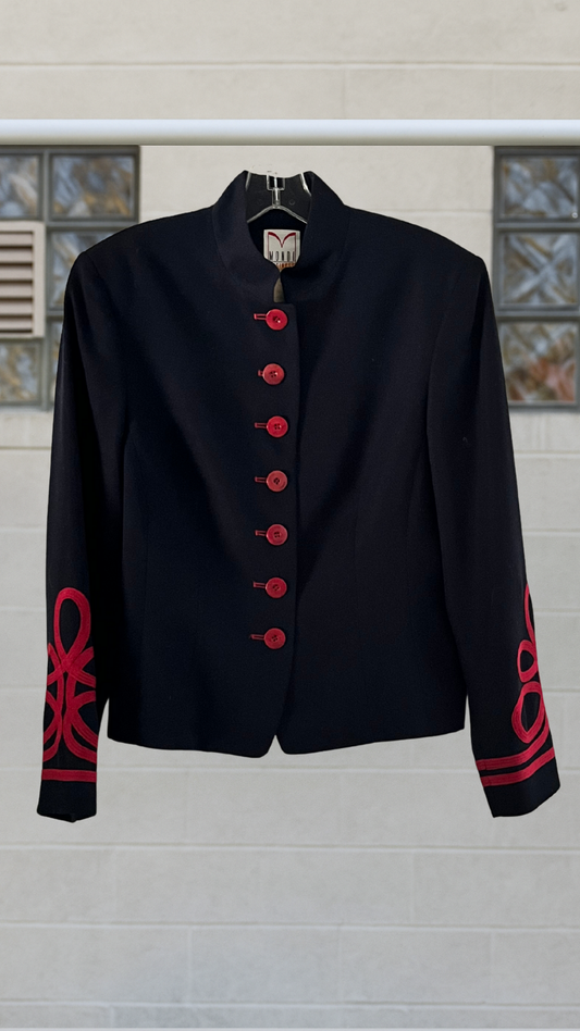 Navy blazer with red buttons and designs on sleeves against a light background