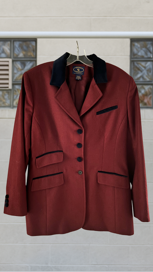 A deep crimson wool blazer with black velvet collar, covered buttons, and asymmetric pocket flaps.
