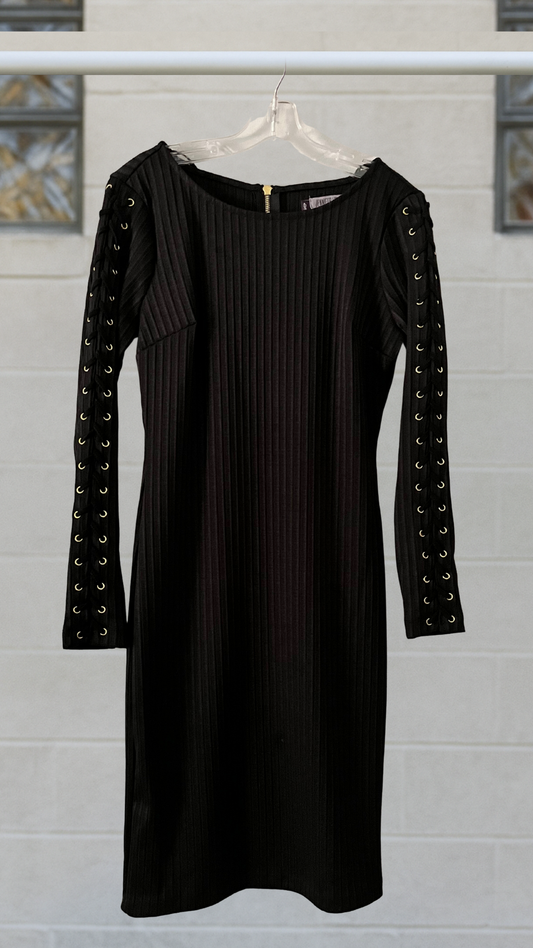A black ribbed bodycon dress with gold grommet long sleeves and a bold zipper back
