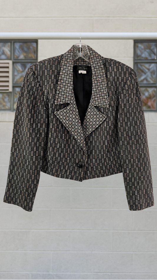 Orange, yellow, and green patterned jacket on a hanger against a light gray wall with decorative elements.
