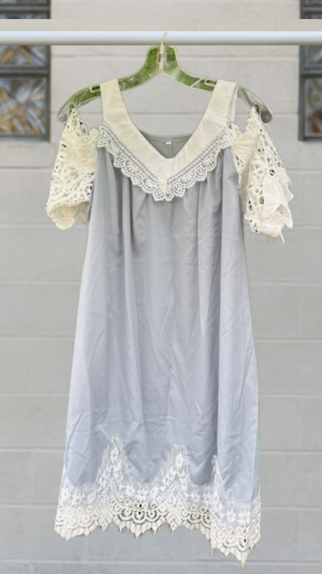Pale gray off-the-shoulder tunic with ivory lace sleeves, scalloped hem, and oversized drape, displayed on hanger.

