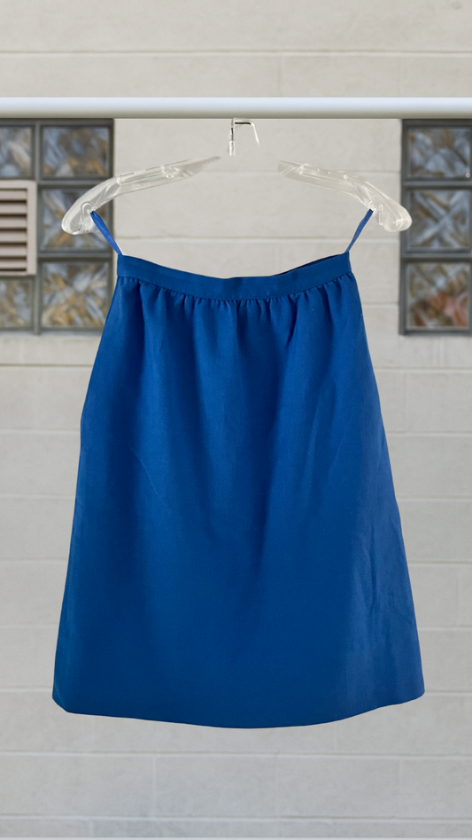 Blue skirt on a hanger against a light-colored wall with decorative elements.