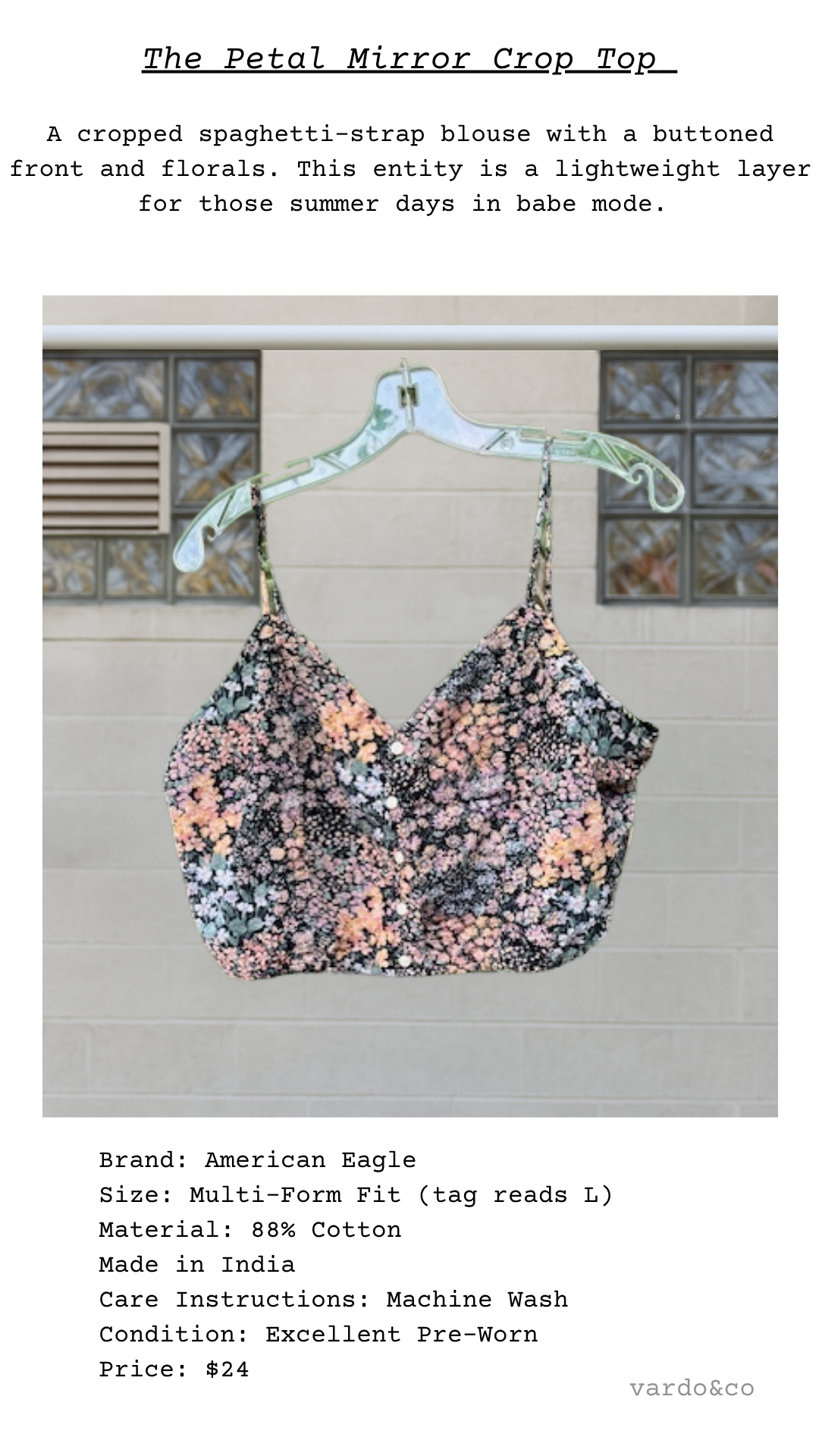 The Petal Mirror Crop Top displayed on a clear hanger against a soft neutral backdrop, showing floral pattern and button-front design
