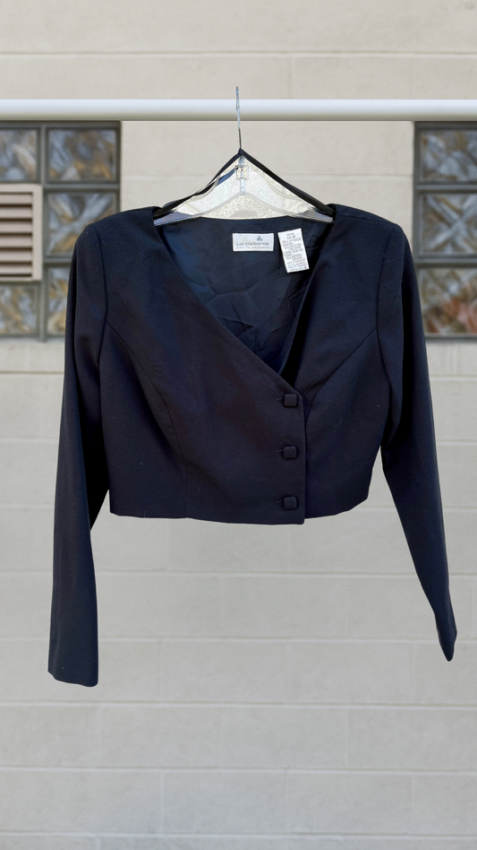 Cropped asymmetrical black blazer with fabric-covered buttons and shoulder pads.