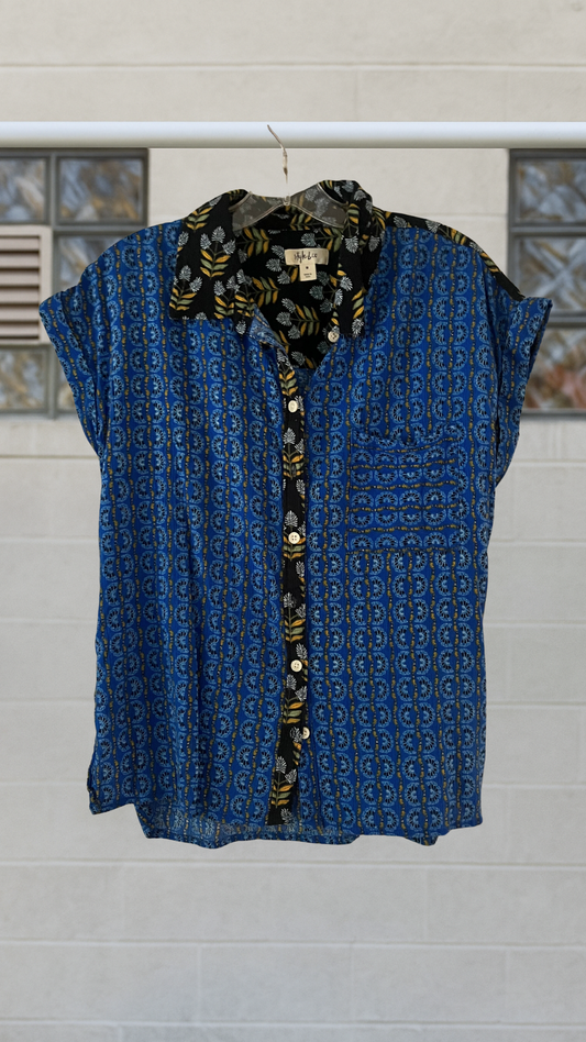 Blue patterned  shirt with a floral collar, hanging against a light-colored wall.