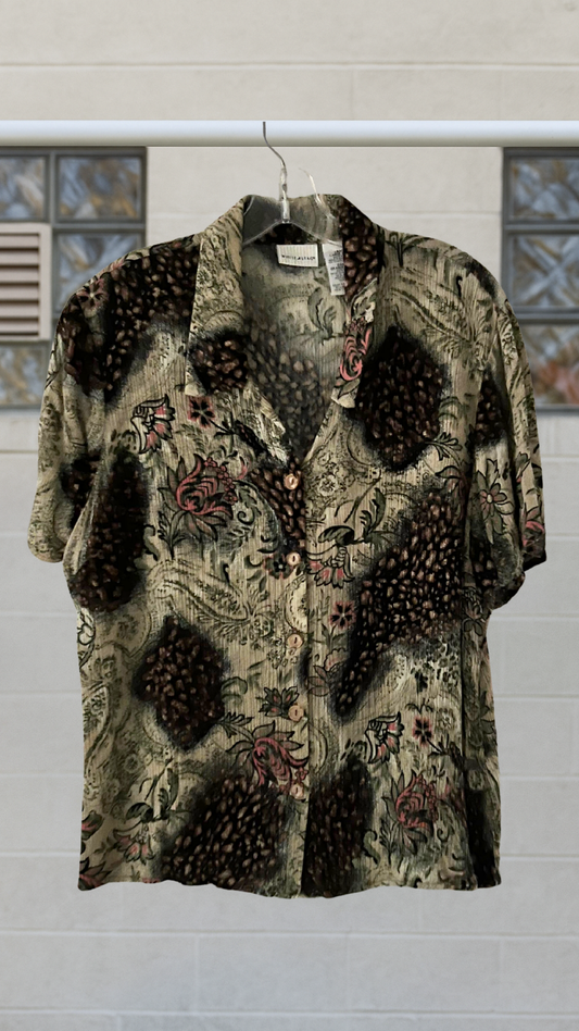 Button down shirt with floral patterns on a hanger against a neutral background