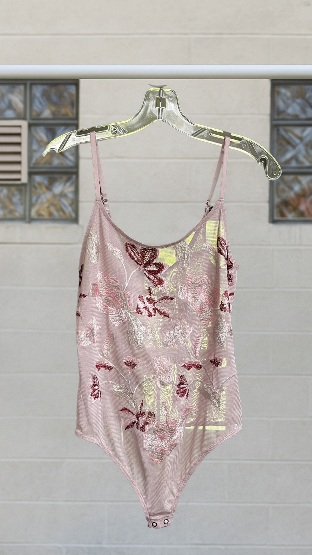 Mauve mesh bodysuit with floral embroidery in red, blush, and sage, hanging on clear hanger.