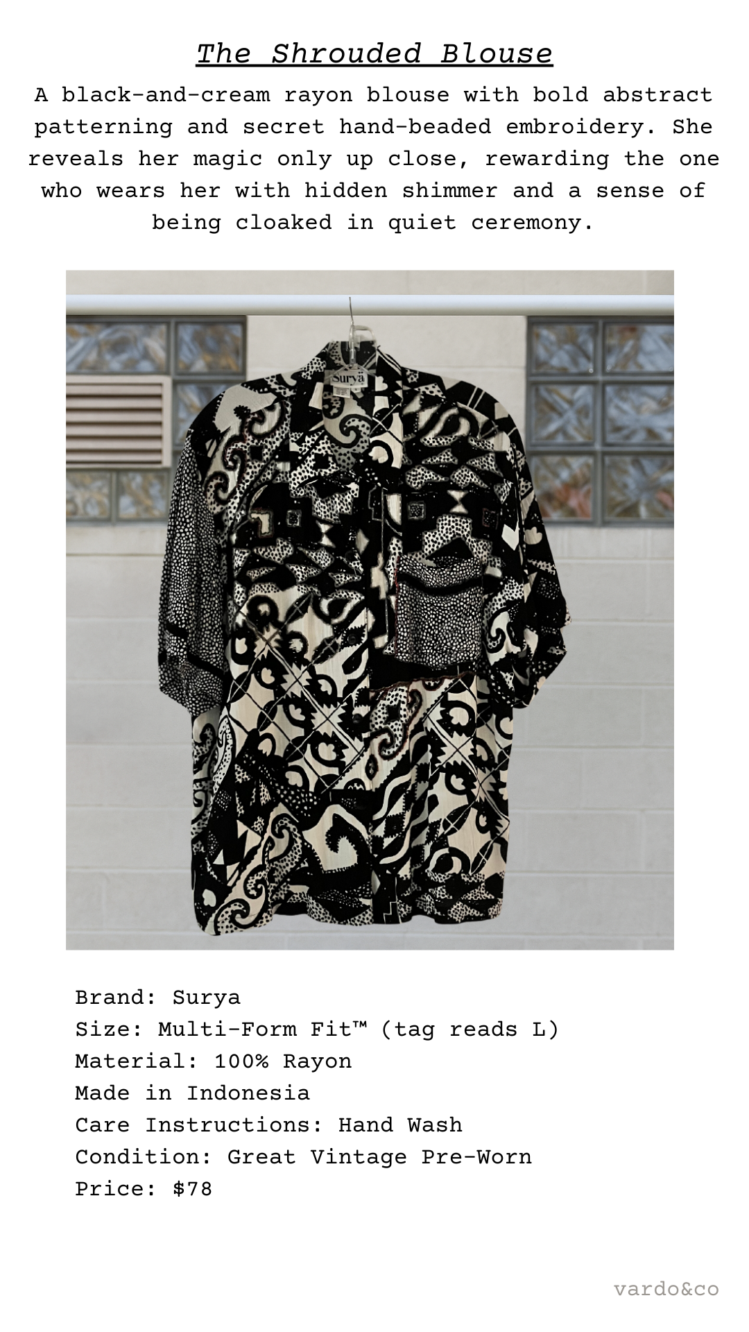Black and cream shrouded blouse with abstract pattern against a tiled wall.