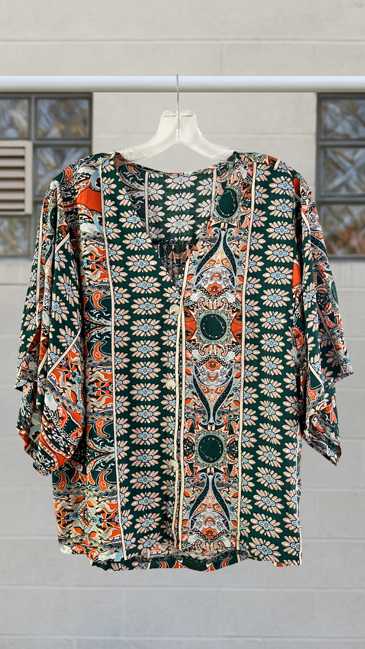 a green and orange patterned button down shirt on a neutral background