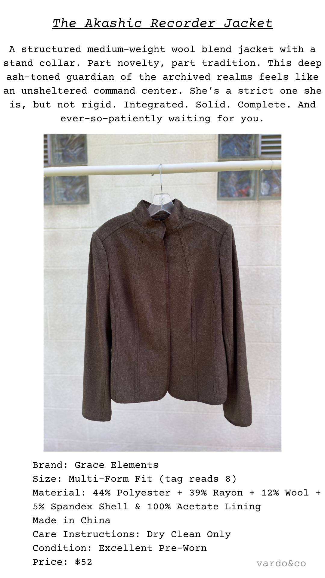 The Akashic Recorder Jacket displayed on a hanger outdoors; deep brown tone, mock neck, and minimalist silhouette centered on concrete wall background
