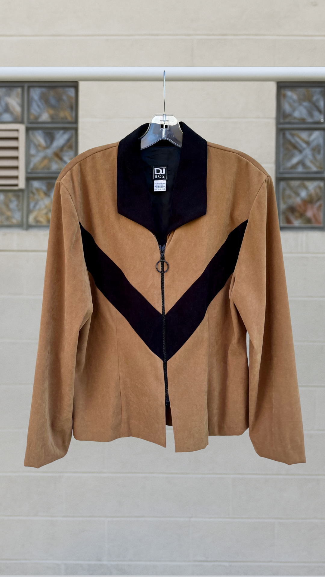 Tan and black chevron zip-up jacket with wide lapel and soft drape, vintage style hanging against a pale wall background.