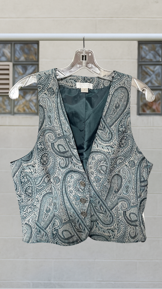 Vintage blue paisley vest with deep V neckline and glossy lining, hung on a clear hanger against a block-glass background.