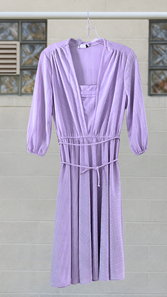 Lavender dress hanging against a tiled wall background